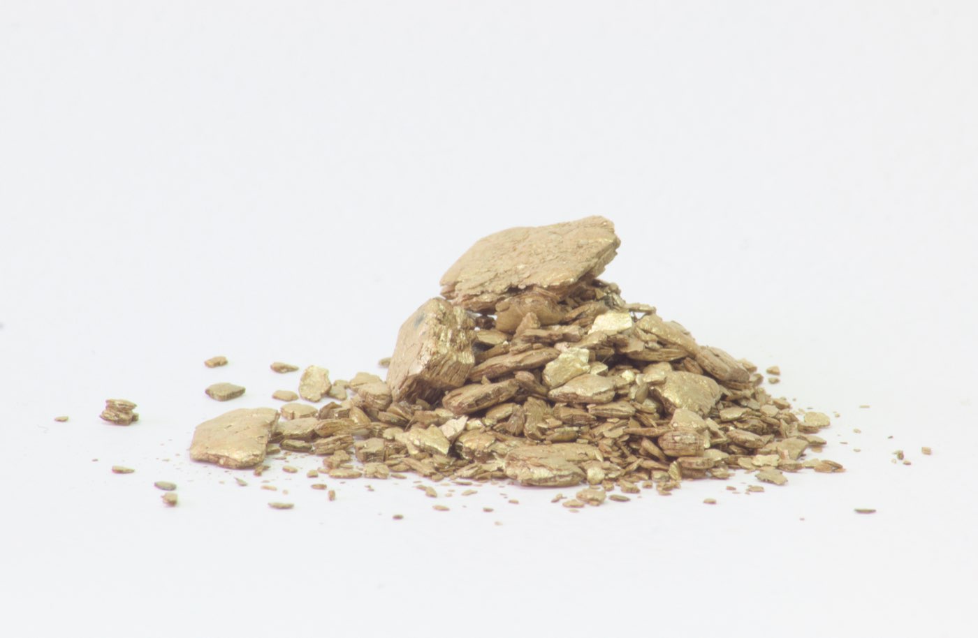 Flocons de vermiculite gris-doré en vrac entre les solives d'un grenier